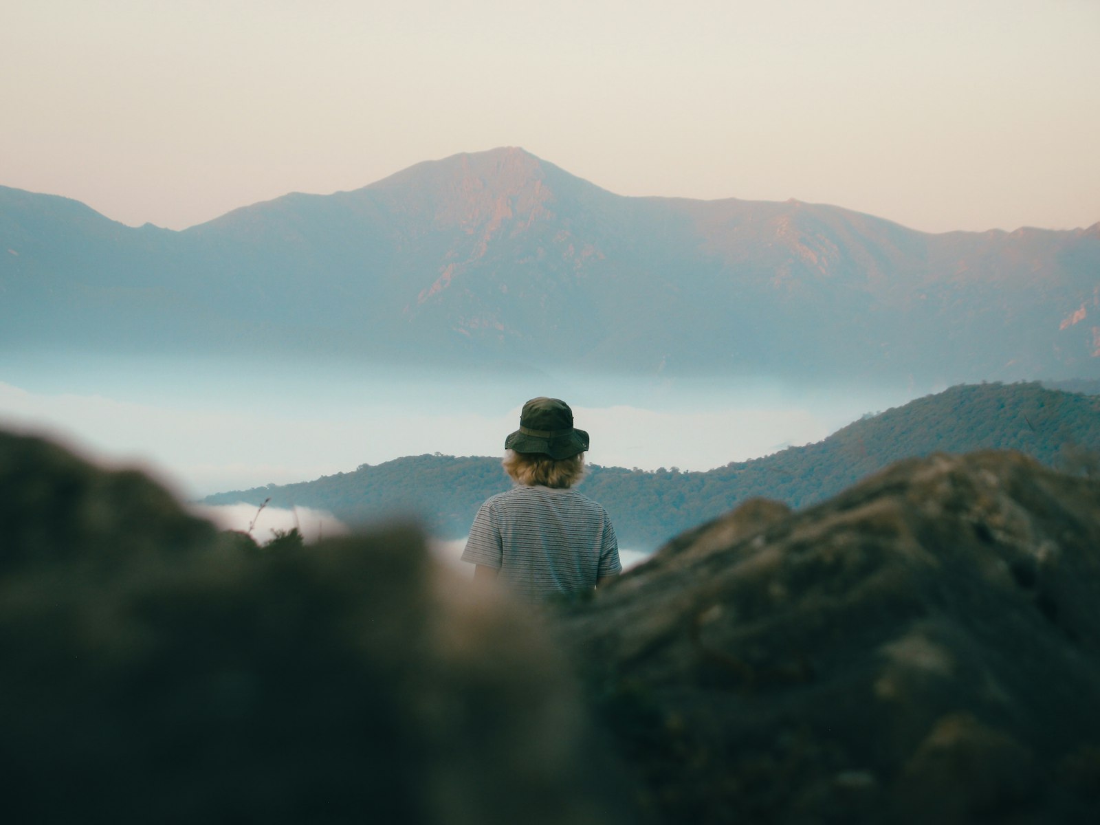 A person in a hat looking out over misty mountains